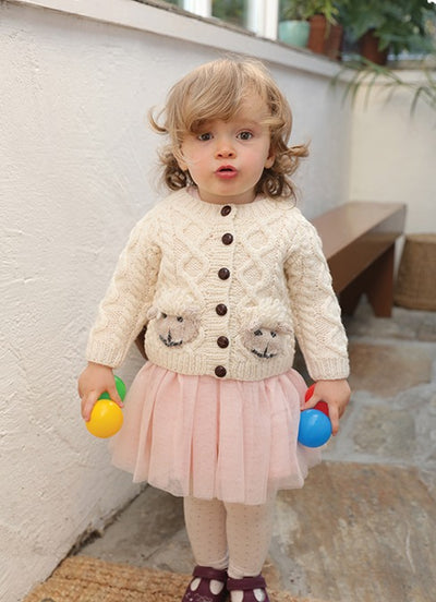 Aran handknit cardigan for kids. cute sheep faces on 2 front pockets. Aran stitches on sleeves and body . Traditional brown buttons on front . colour natural.
